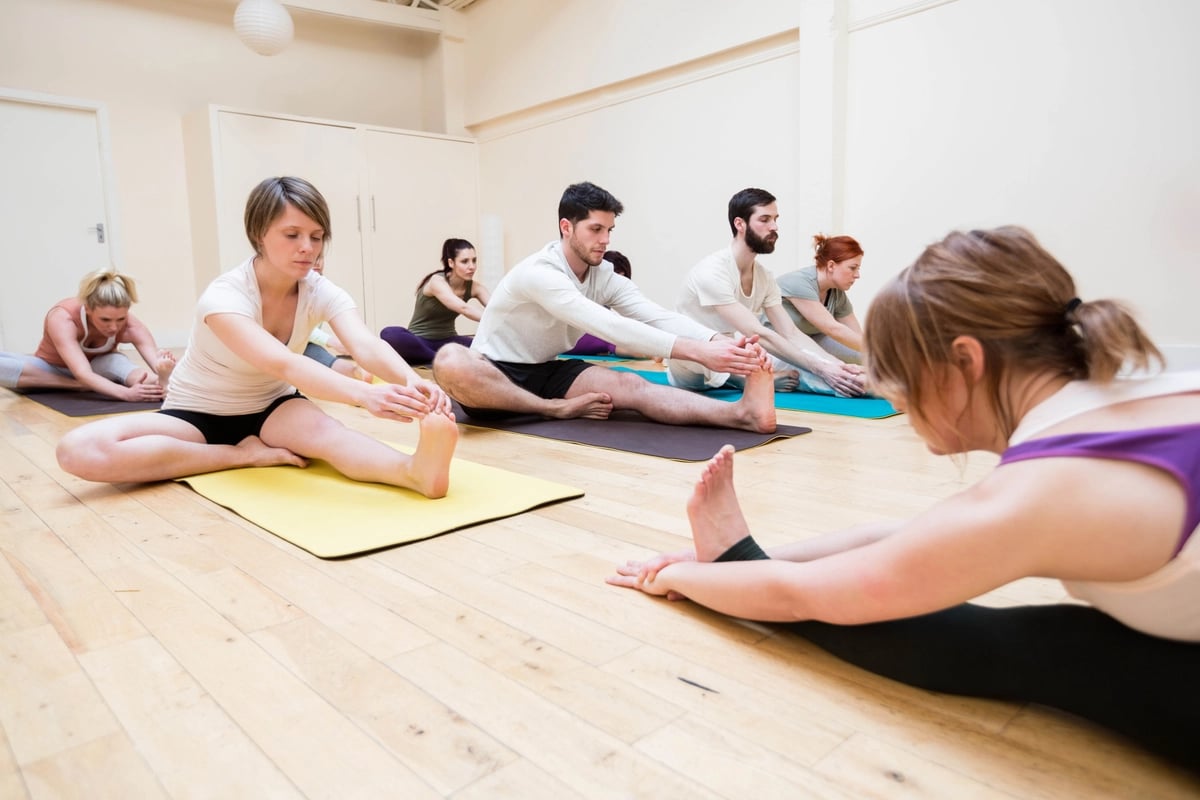 trainer-assisting-group-people-with-stretching-exercise