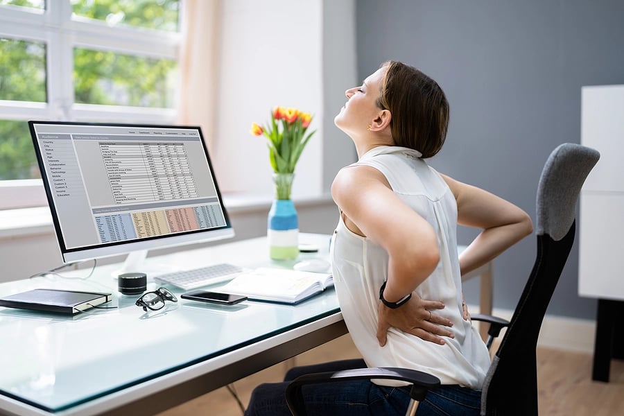 Female with lower back pain at her workstation