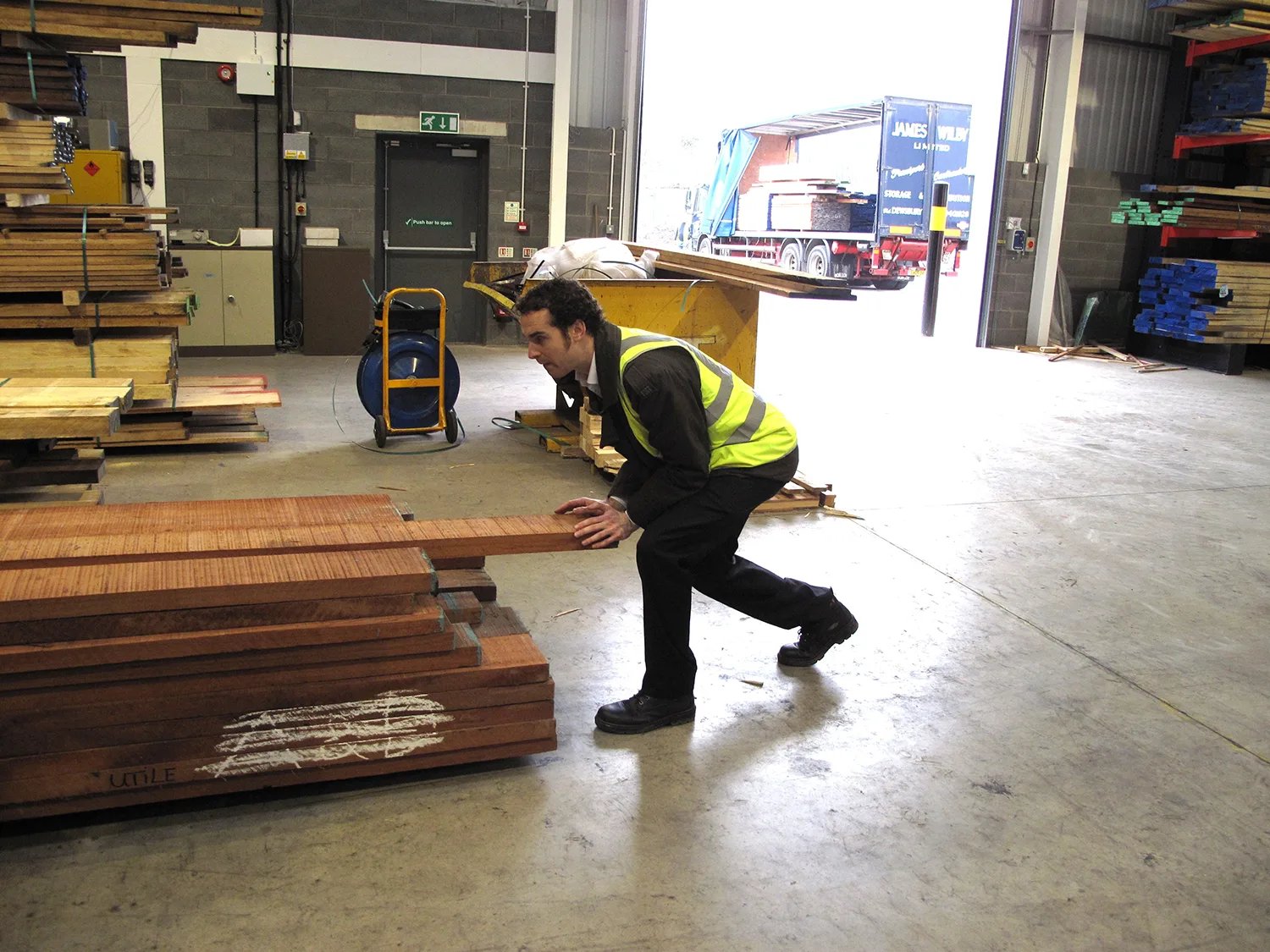 Man pushing wooden planks in warehouse