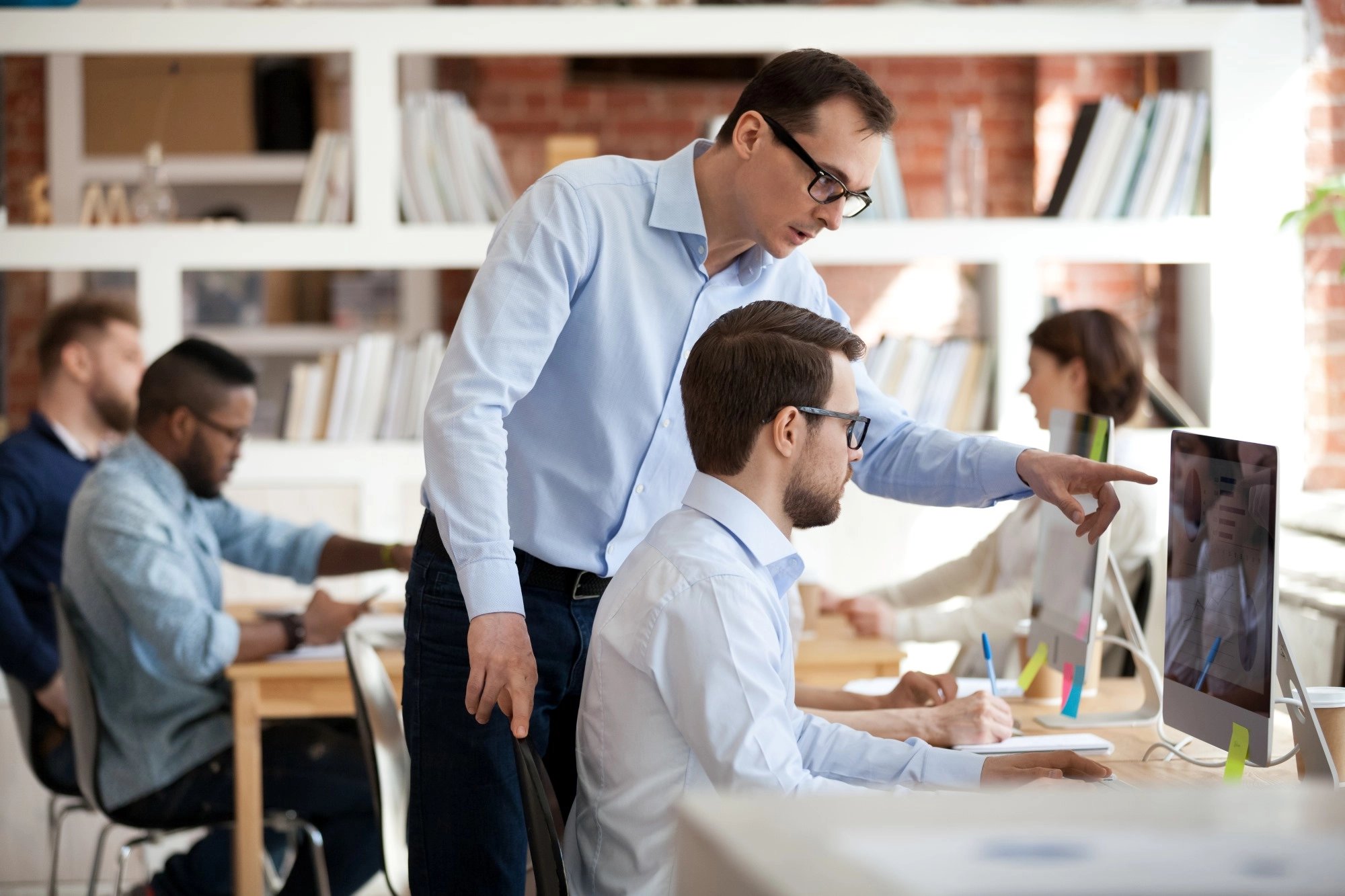 Manager helping male colleague with computer task
