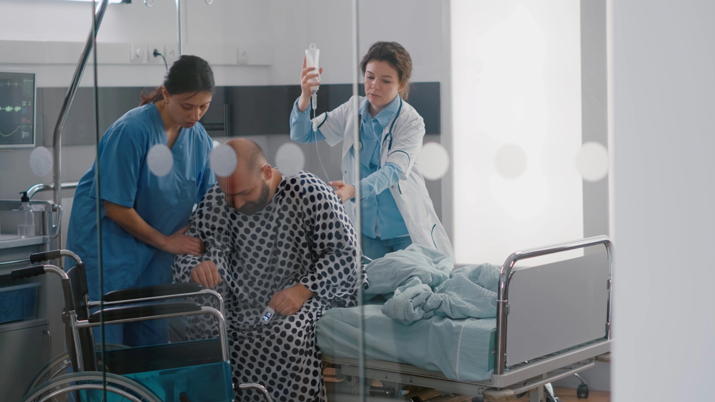Nursing team helping man out of bed - People Moving and Handling in action