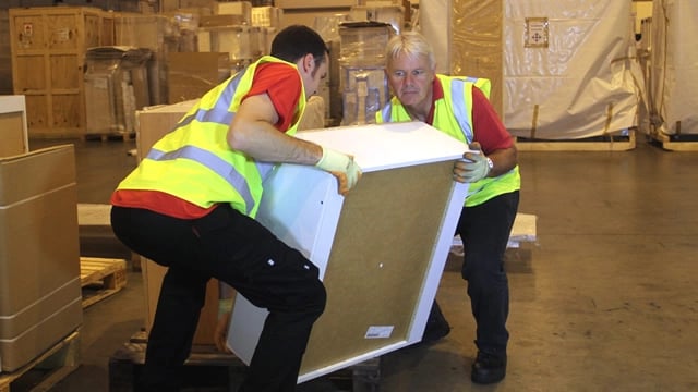 Colleagues perform a team lift of furniture item