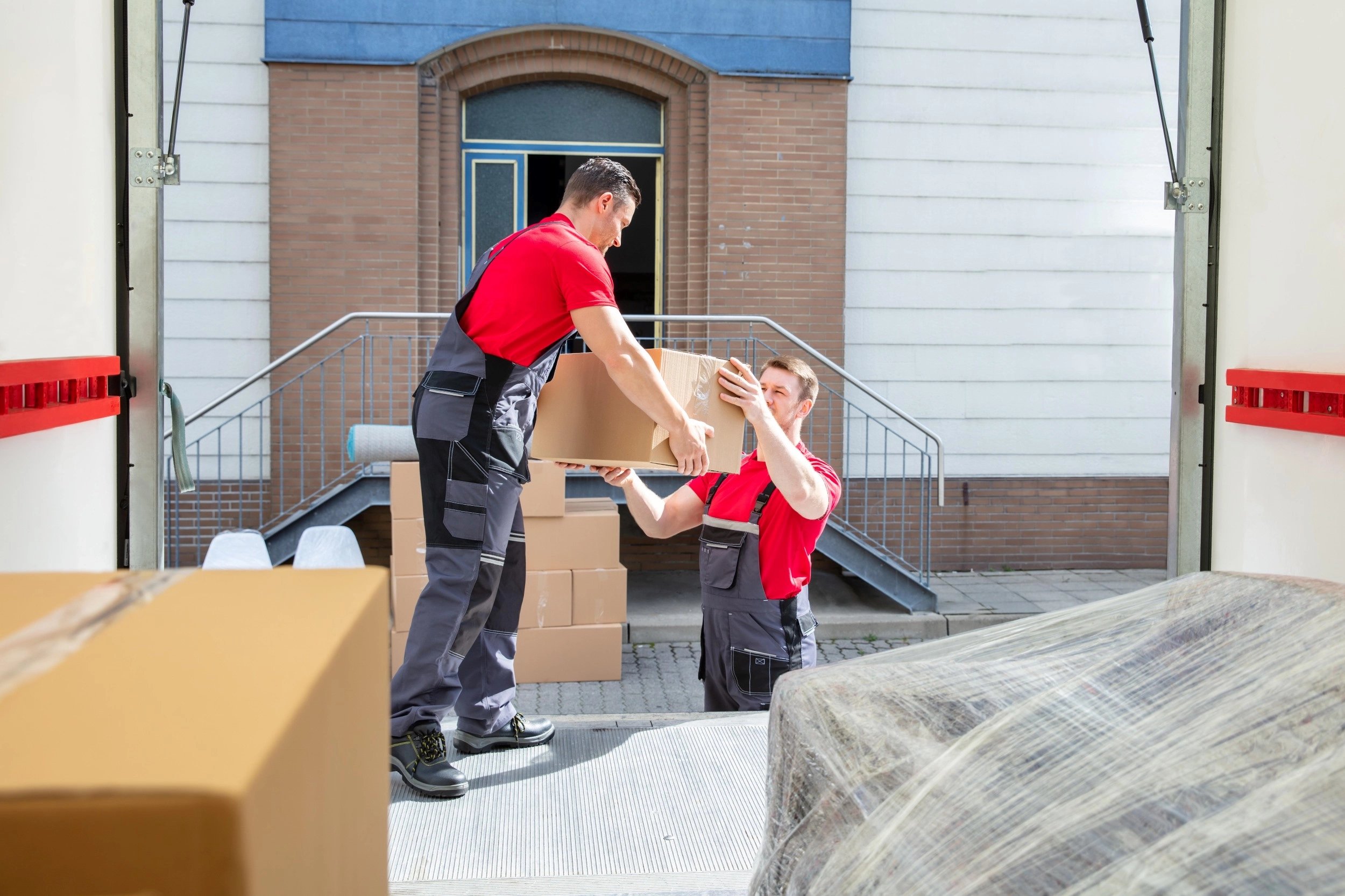 Young men putting boxes into rear of lorry