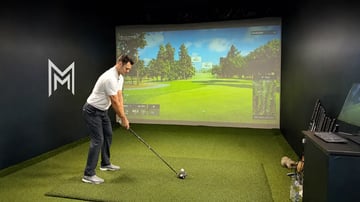 Golfer mid-swing beside an alignment rod during a focused training drill.
