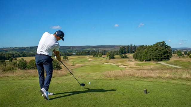 Golfer driving the ball on an outdoor course.