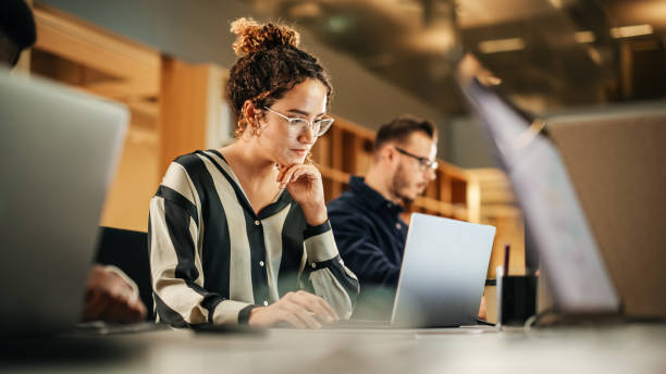 Focused businesswoman working on laptop, managing underperformance.
