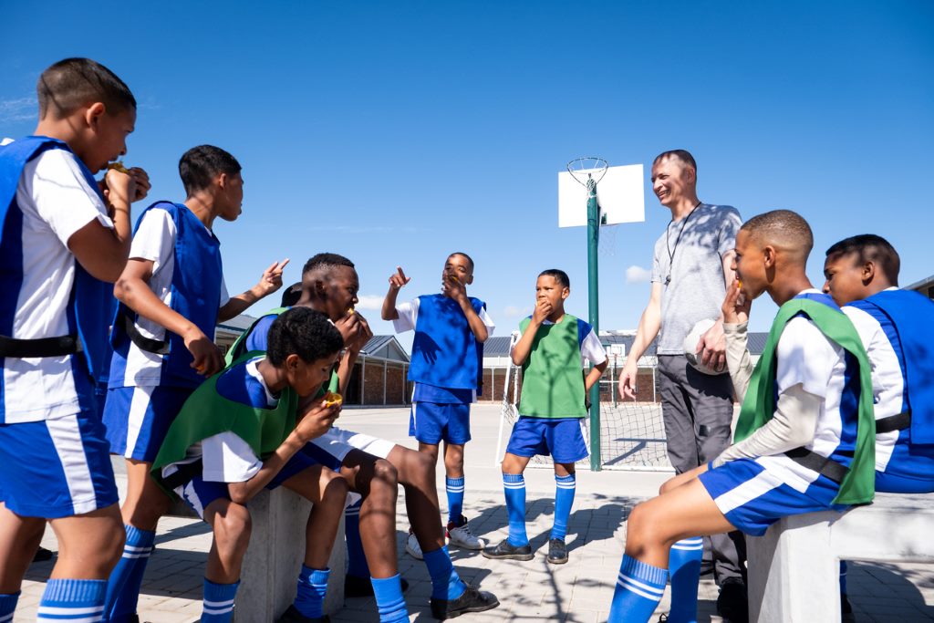 A team of soccer players and their coach enjoy healthy oranges for their half time snack