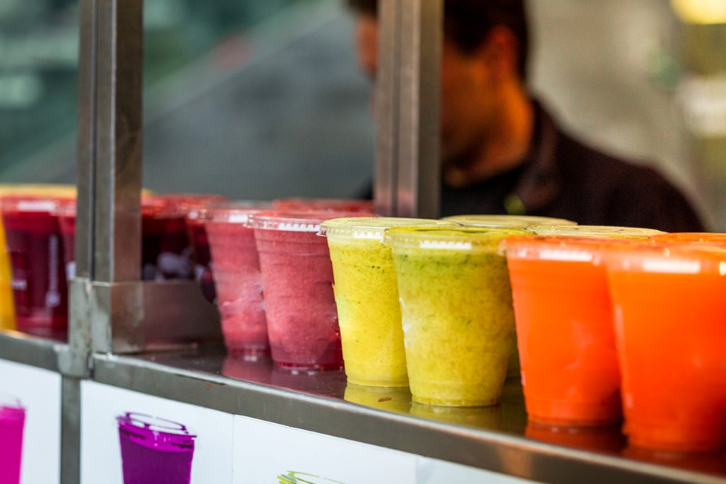 freshly made fruit juices and smoothies on display in a row and for sale at a food and drink market