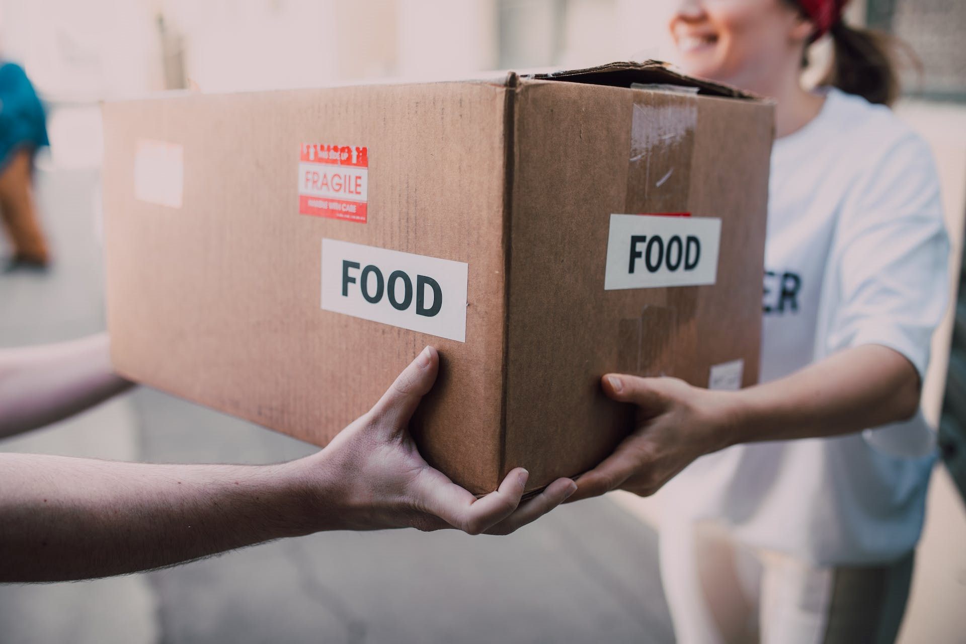 a box labeled with the word food being handed over to another person