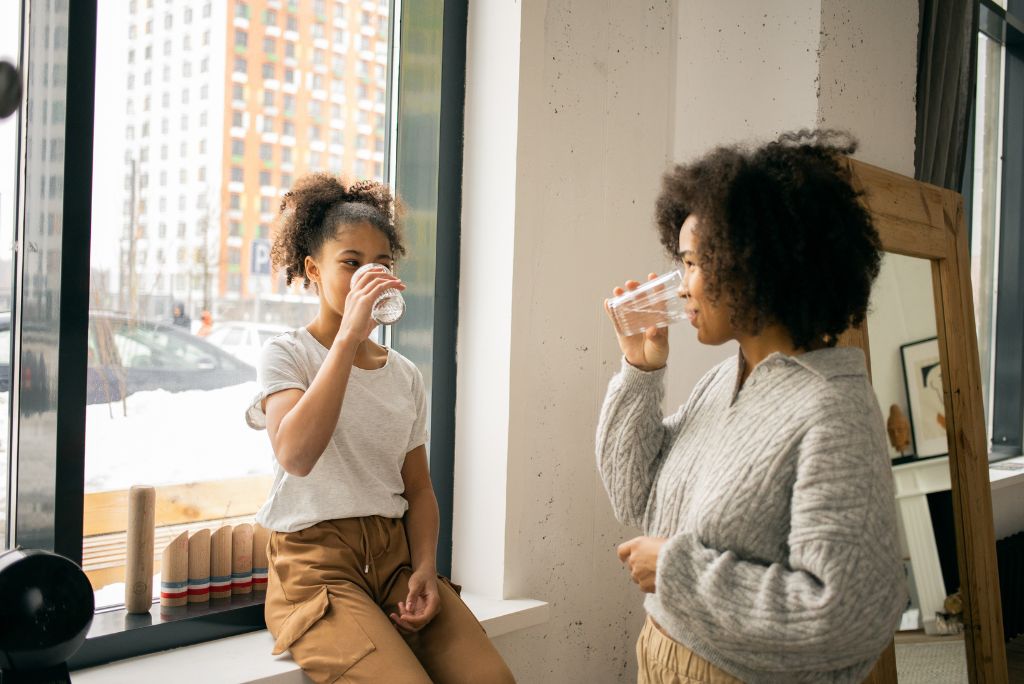 une mère et sa fille boivent de l'eau dans leur cuisine