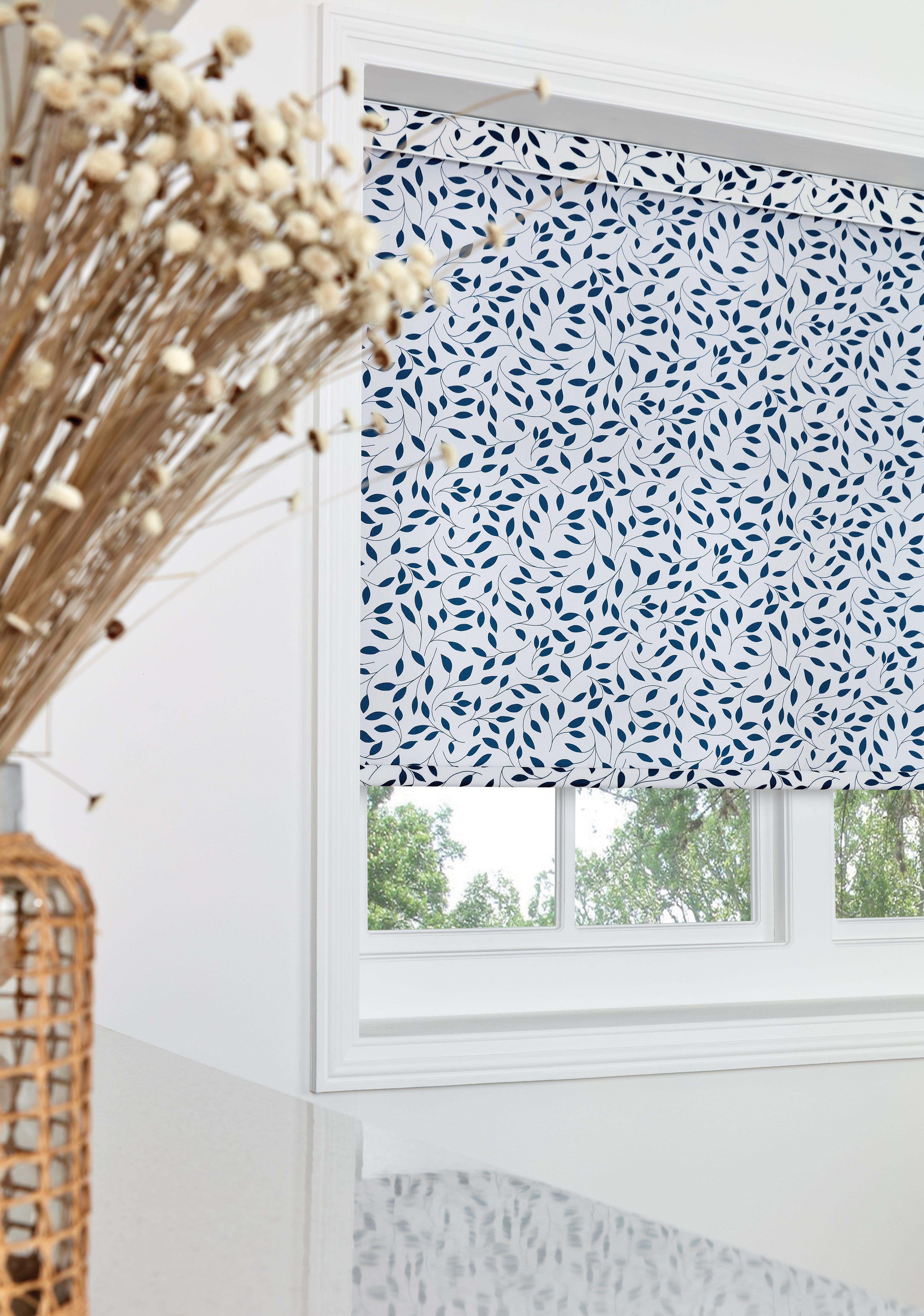 Blue leaf pattern roller blind in a white framed window.