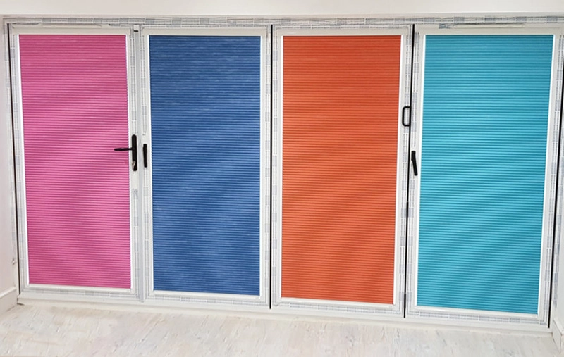 Colorful pleated blinds on folding doors, pink, blue, orange, turquoise.