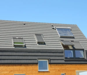 Modern house roof with skylights, solar water heater, and grey tiling.