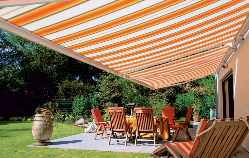 Orange and white striped awning shading outdoor dining set on patio.