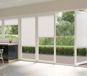 White cellular shades on a sliding glass door overlooking a patio and garden.