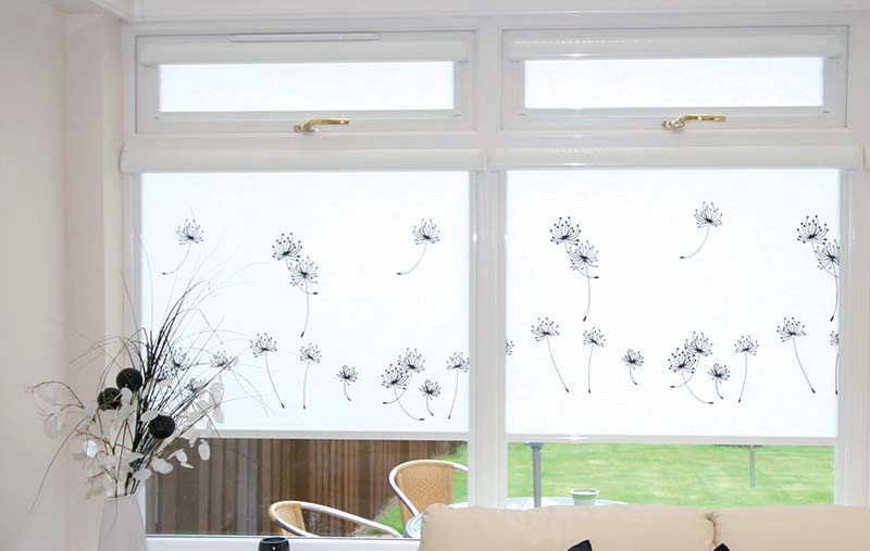 White roller blinds with dandelion design covering a window, providing privacy and light control.