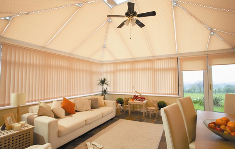 Bright conservatory interior with vertical blinds on windows and pleated blinds on the roof.