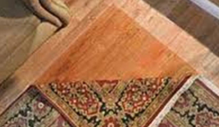 Fading rug being covered with window blinds material to prevent further sun damage.