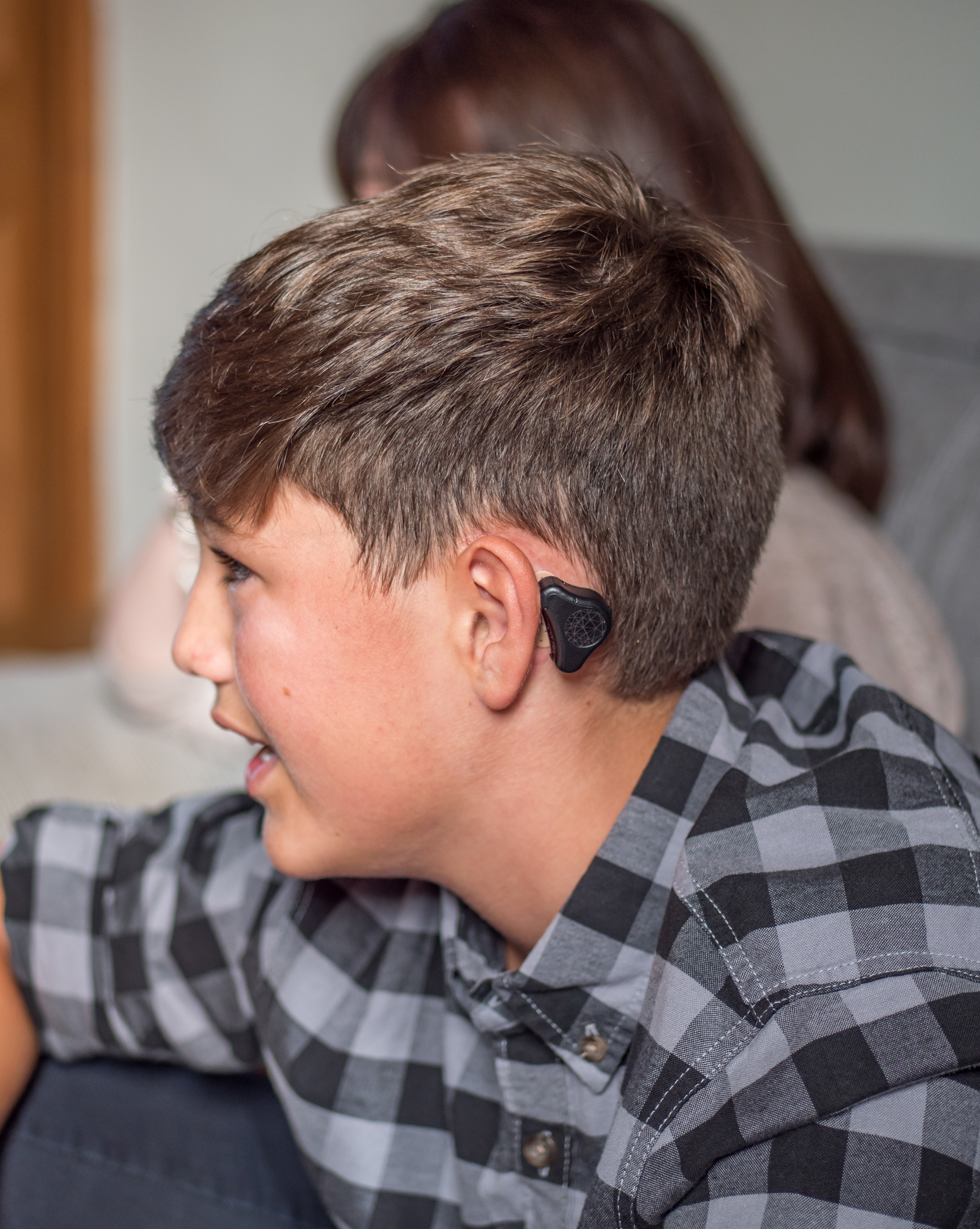 A young boy wearing MED-EL ADHEAR hearing aids
